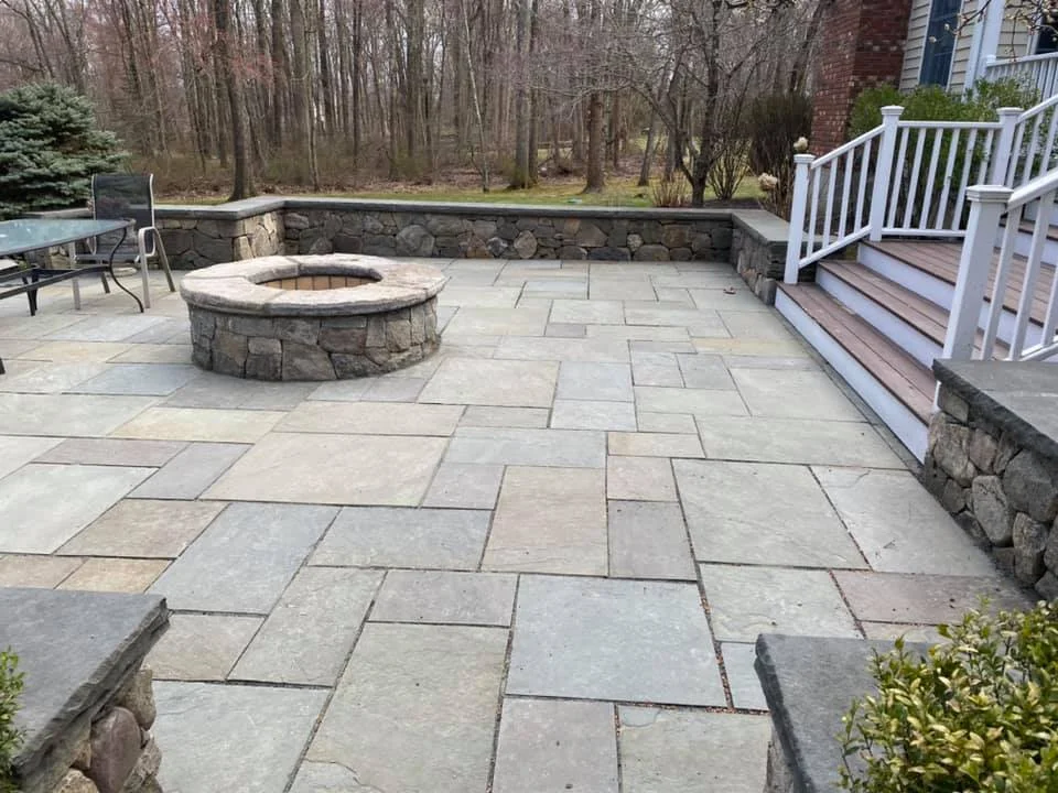 Stone patio with built-in fire feature and seating wall
